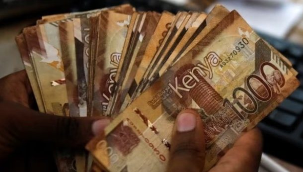 A teller handles Kenya shilling banknotes inside the cashier's booth at an Equity Bank branch